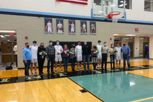 All five senior boys standing with their parents, being honored before the big game against Washington.