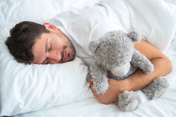 The man sleeping with a soft toy on the white background